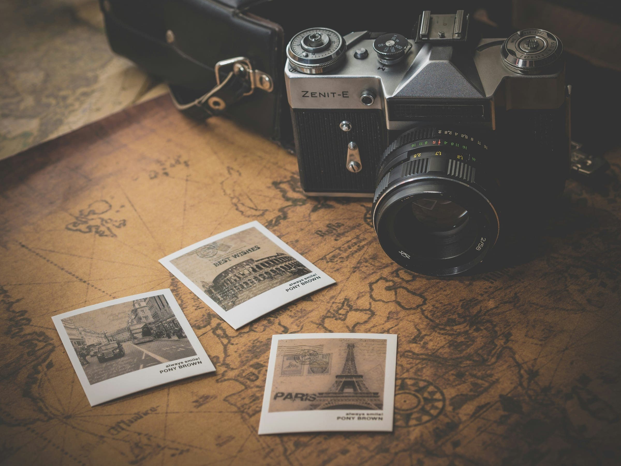 A vintage film camera and three instant prints on an old world map