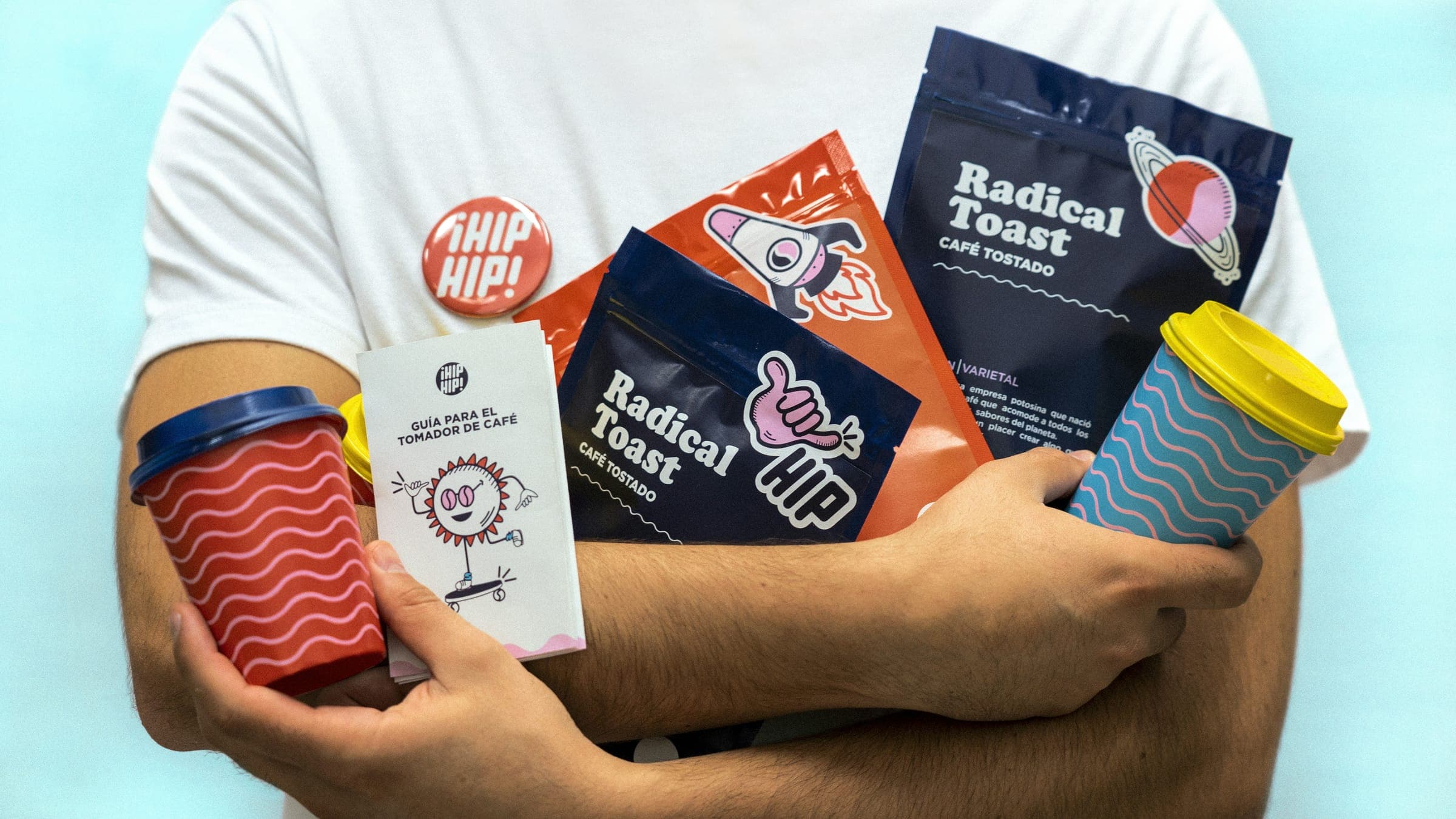 A man holding coffee bags, cups and a booklet from a playful coffee brand