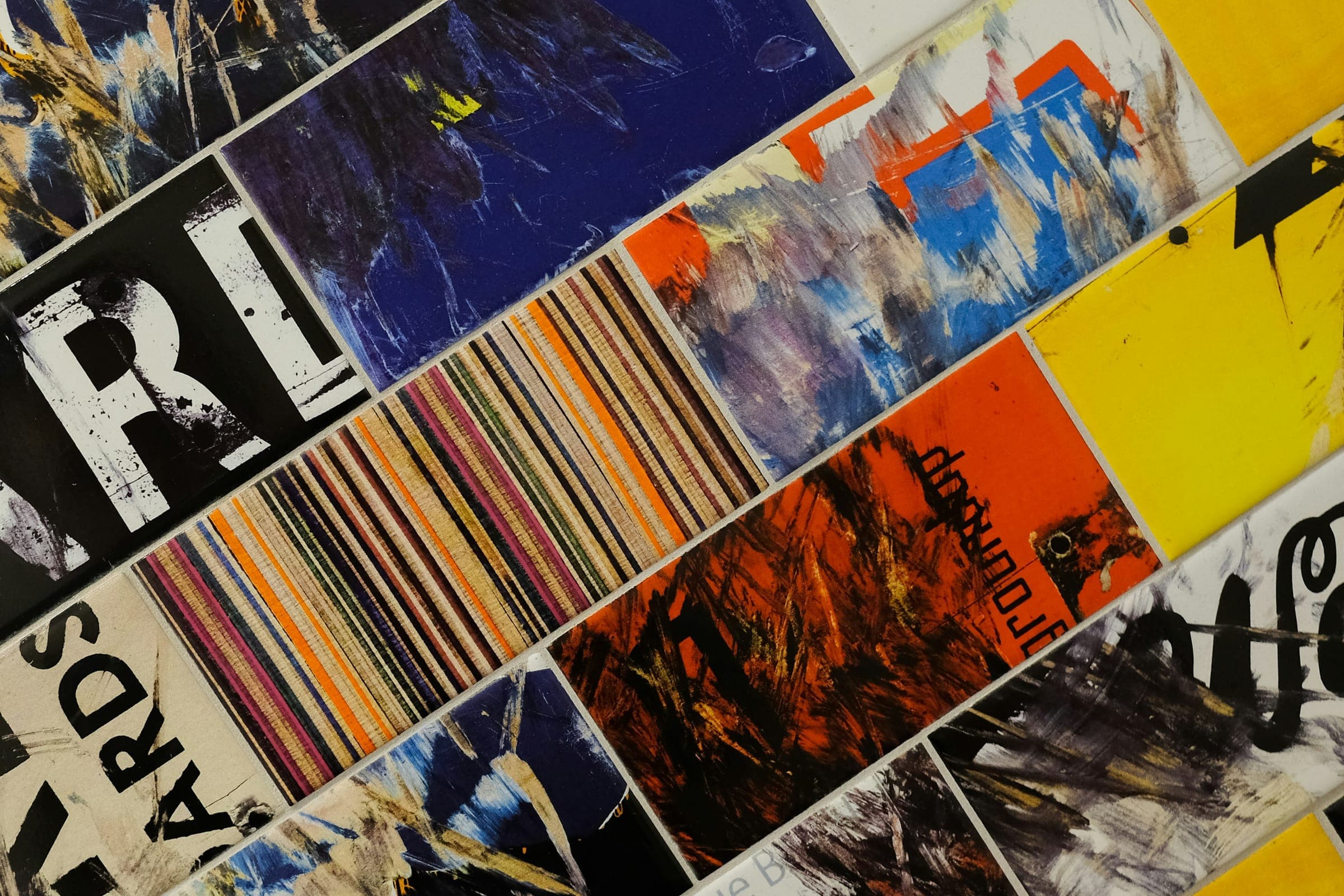Diagonal rows of tiles painted with abstract colourful brushstrokes and lettering
